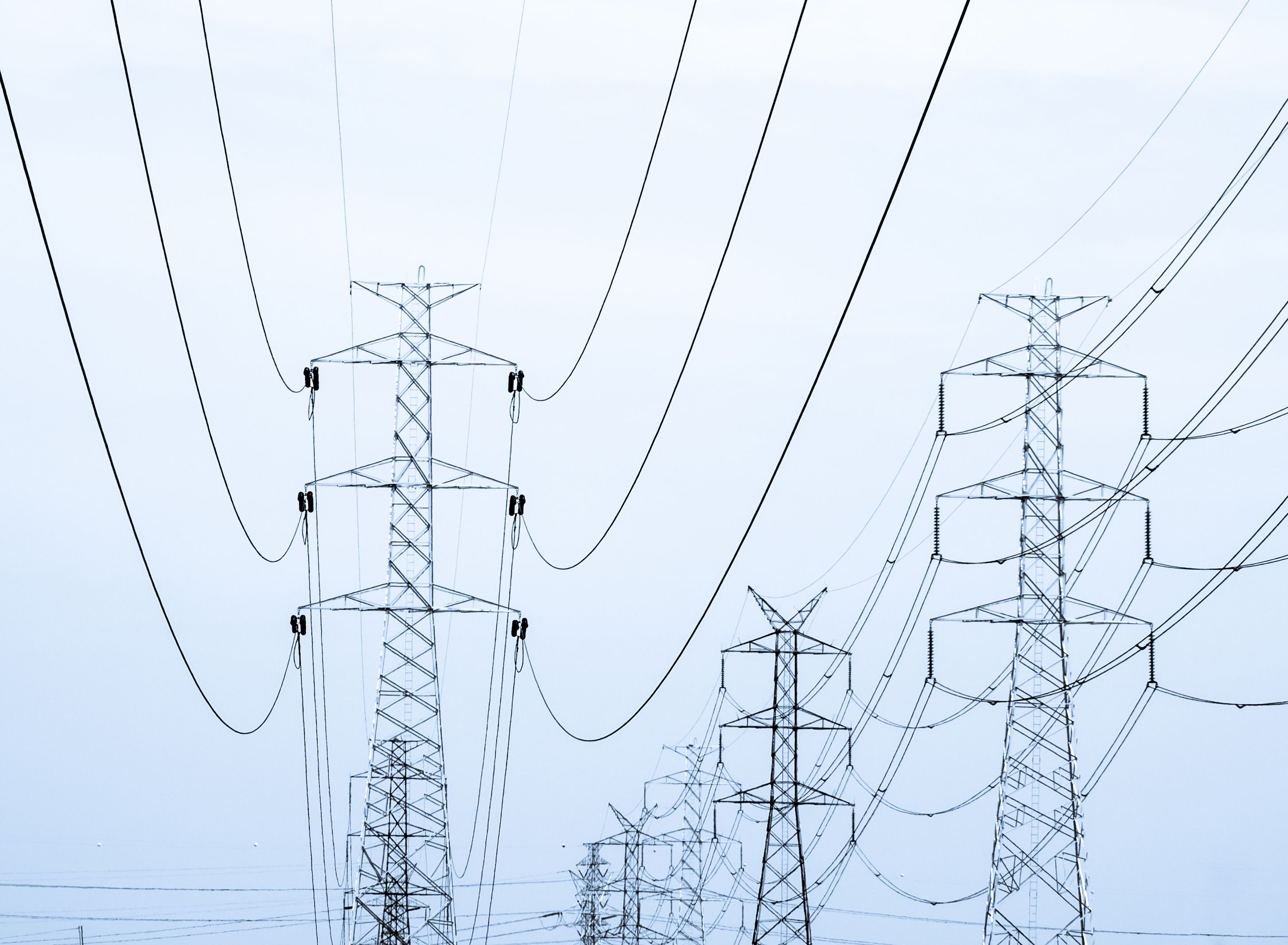 High voltage posts and powerlines in the cloudy sky processed as duotone