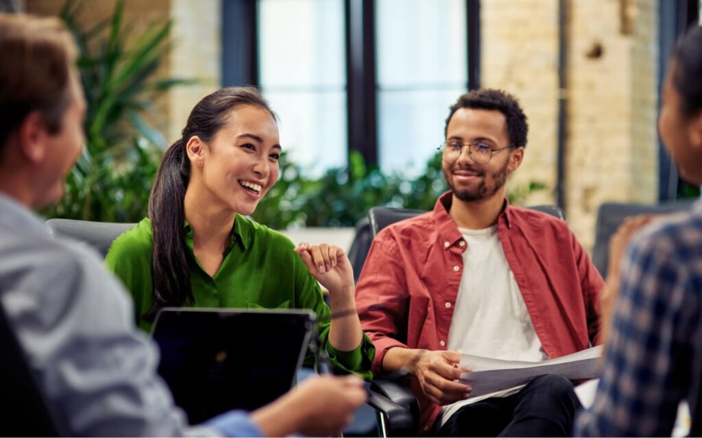 a group of young professionals smile and talk in an office setting