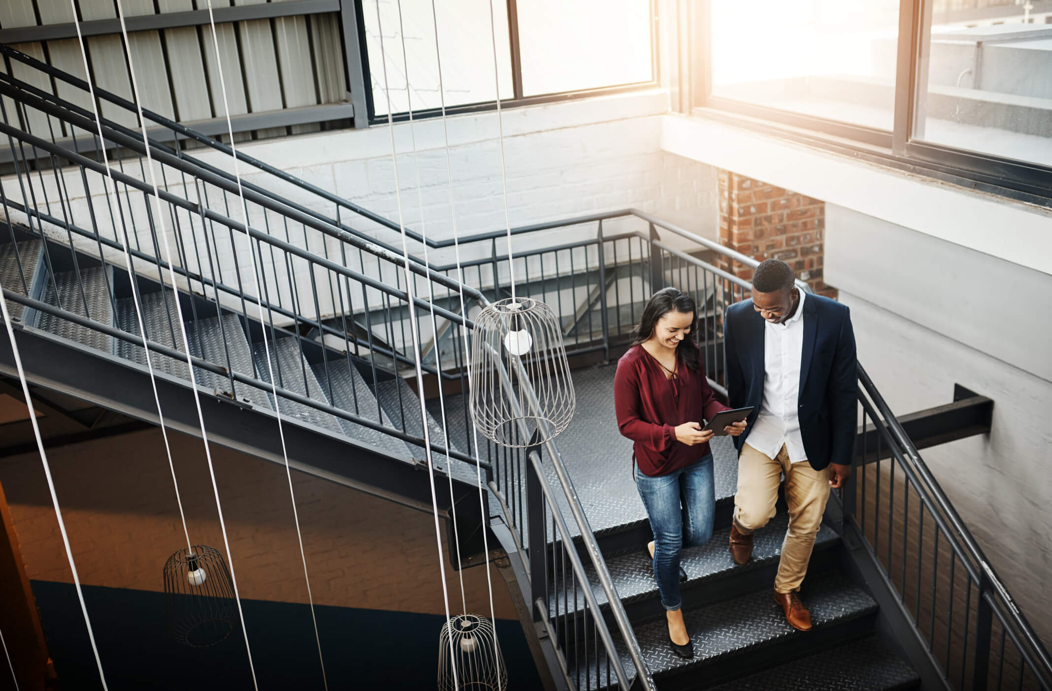 a male and female professional walking down stairs in an office environment