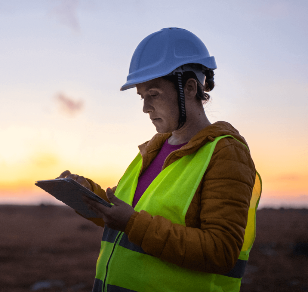 A female technician in safety gear using a tablet