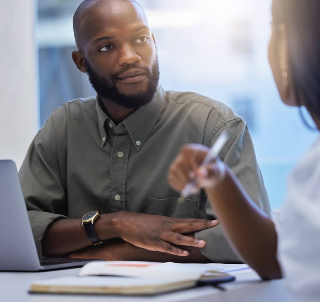 a black male professional in an office environment is looking at a colleague 