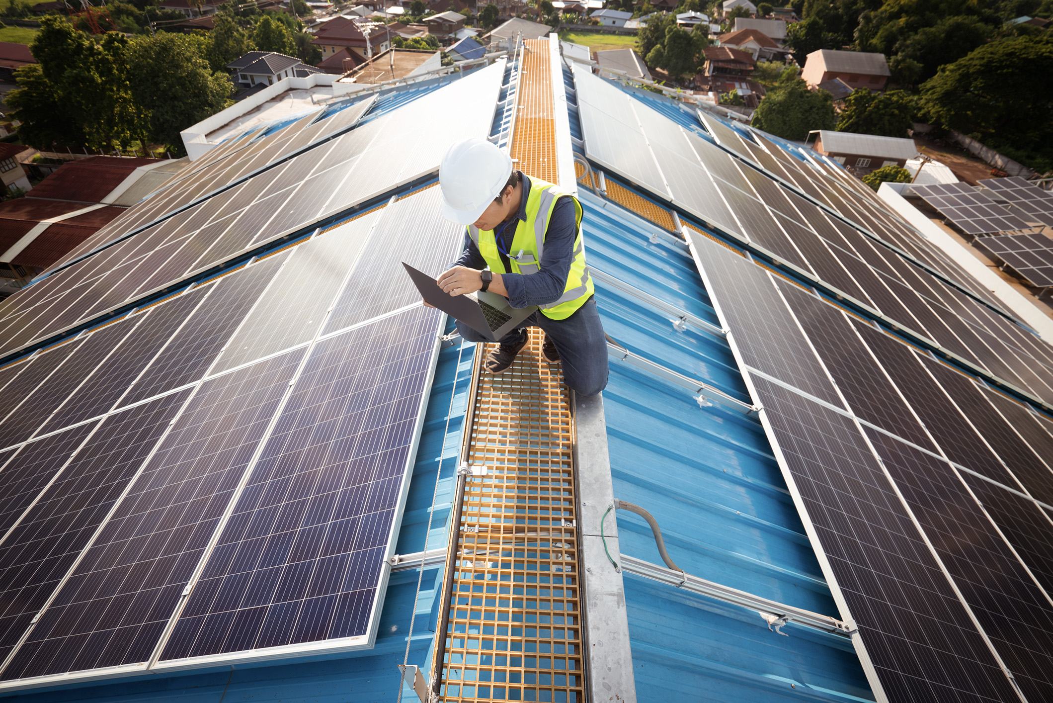 Male on a laptop on a roof with solar panels