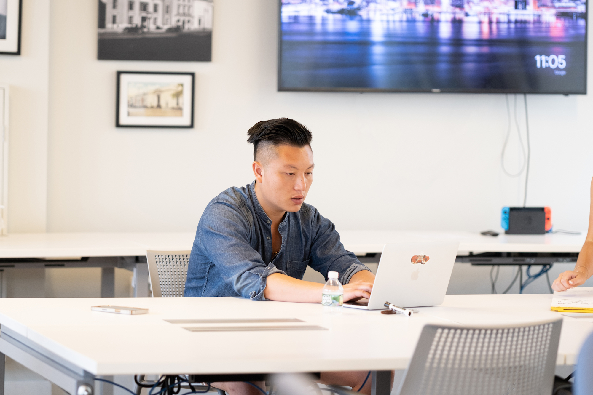 a male professional in an office setting typing on a laptop