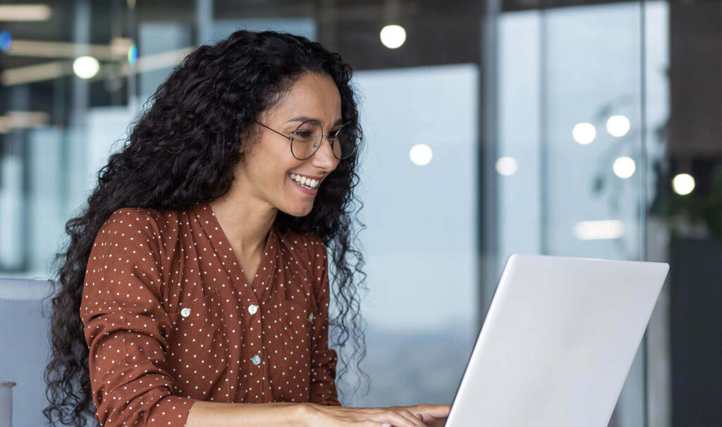 Woman smiling at laptop while typing
