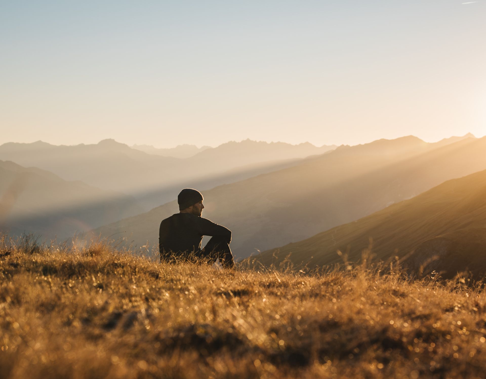 A man sitting at the top of a mountain looking out to the distance