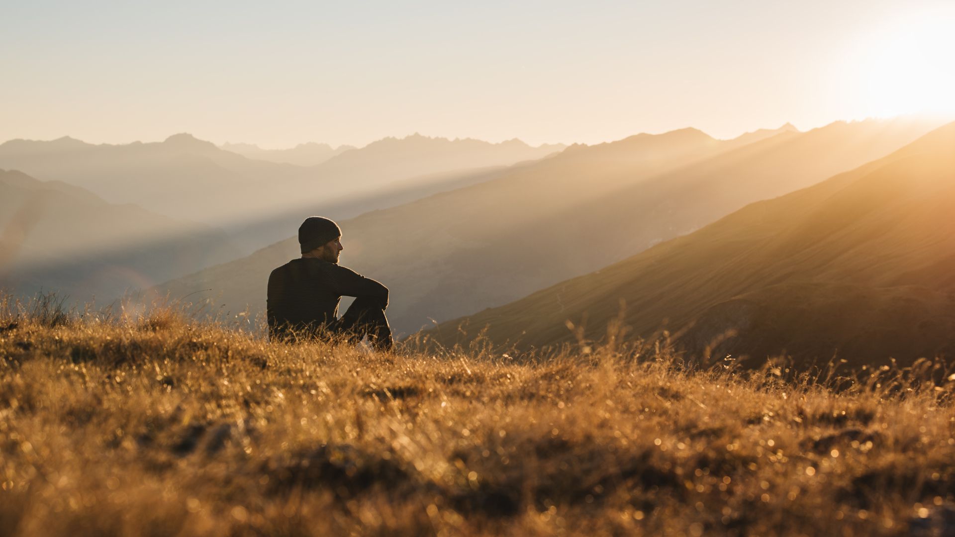 A man sitting at the top of a mountain looking out to the distance