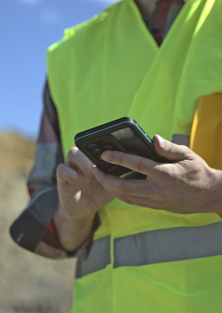 A contractor in a yellow safety vest uses his phone