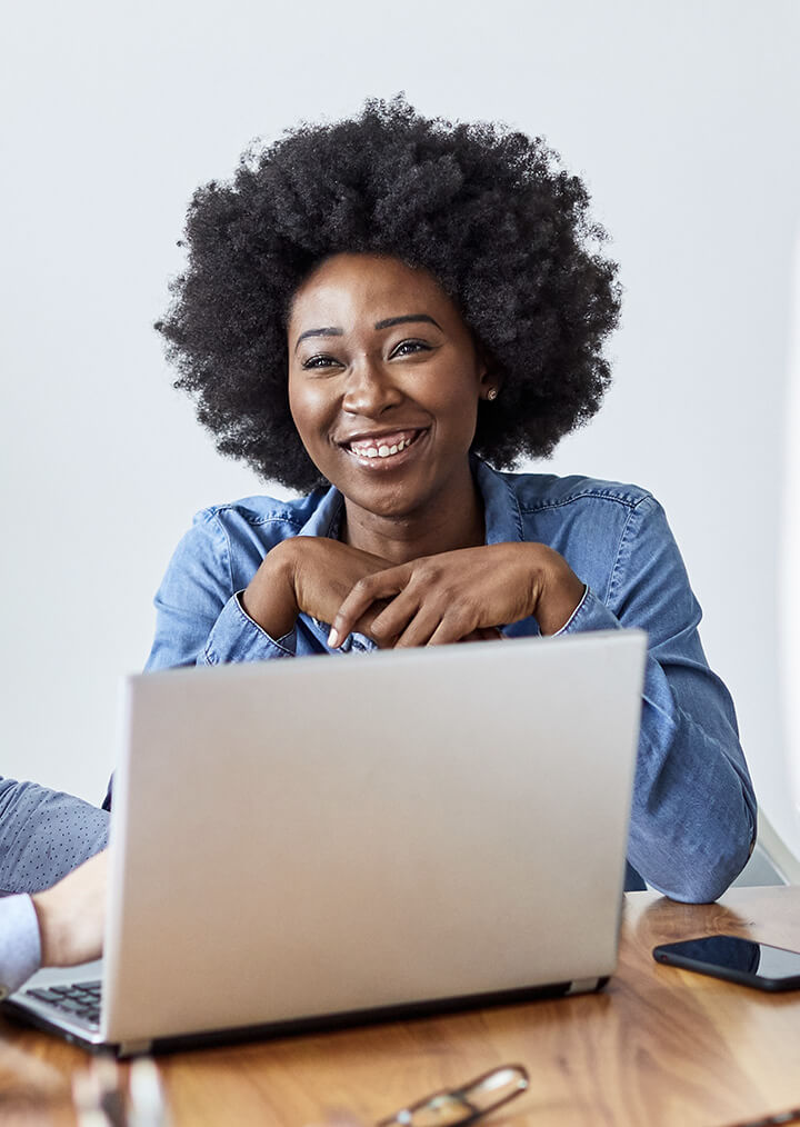A young Black woman smiling in front of a laptop