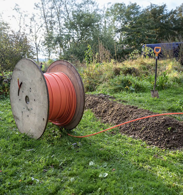 A large spool of fiber cable sits in a grassy yard