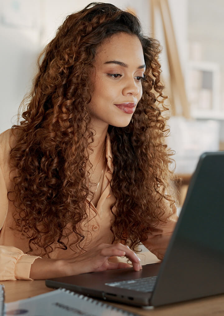 A young female professional works on a laptop in an office setting