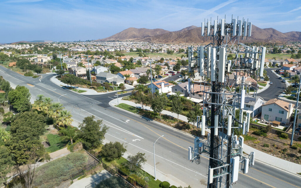 Aerial view of a large cell tower overlooking a suburban neighborhood with roads and houses