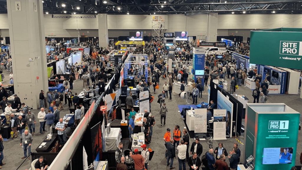 A large trade show floor at the NATE UNITE conference, filled with exhibitor booths, banners, and a crowd of attendees networking and exploring industry-related products and services.