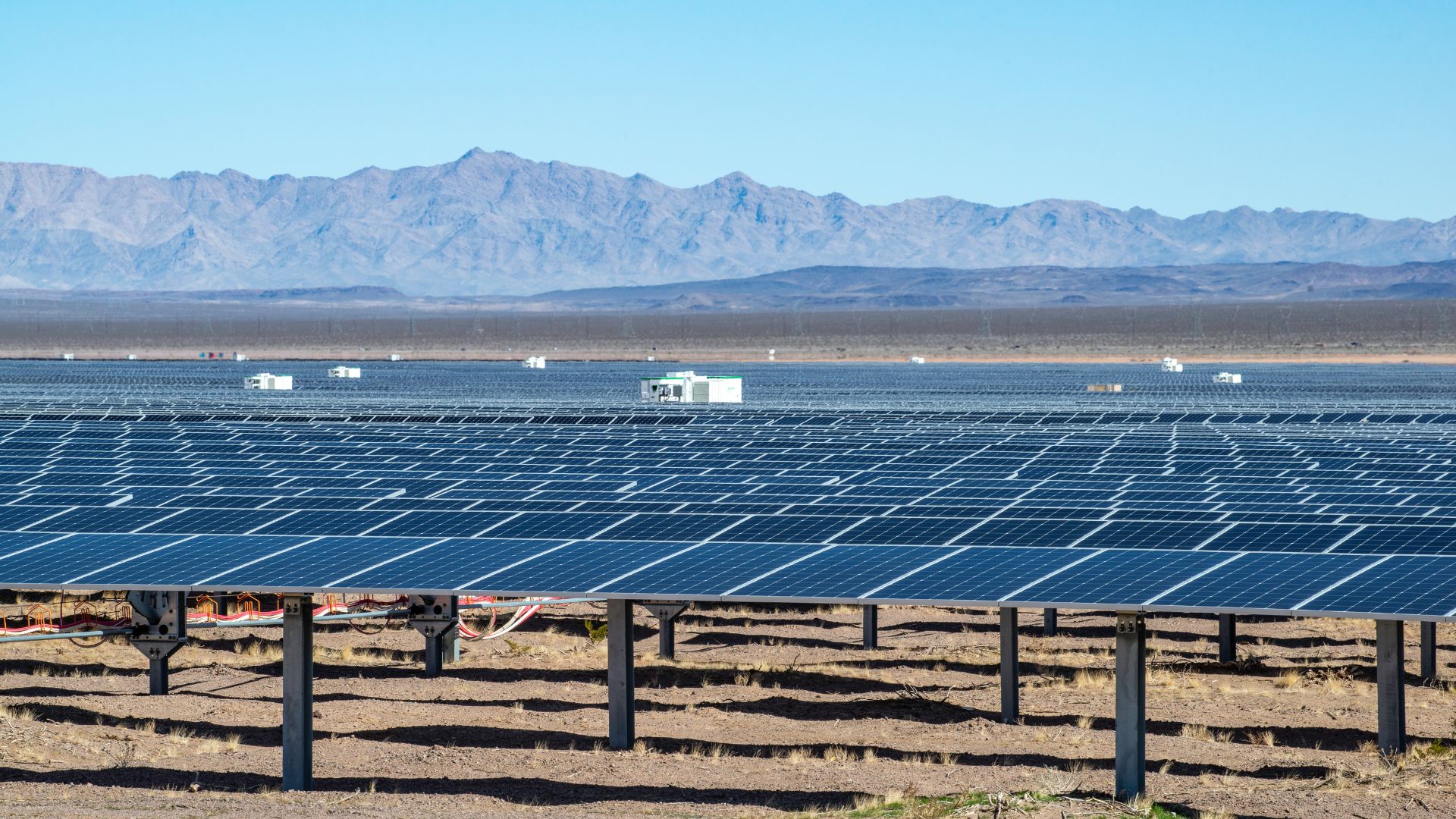 a field of utility scale solar panels with mountains in the background