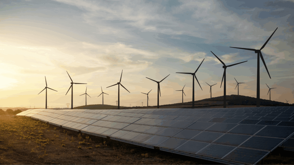 a field of solar panels with wind turbines in the background