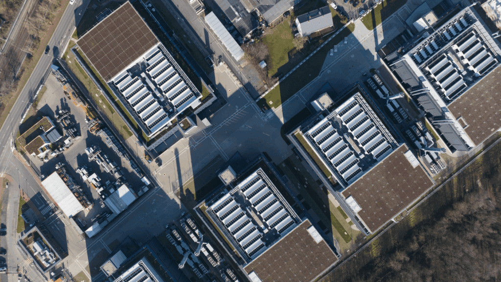 Aerial view of multiple large data center buildings with rooftop cooling units and surrounding infrastructure