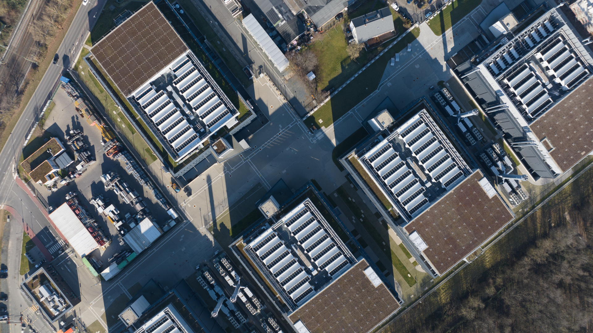 Aerial view of multiple large data center buildings with rooftop cooling units and surrounding infrastructure