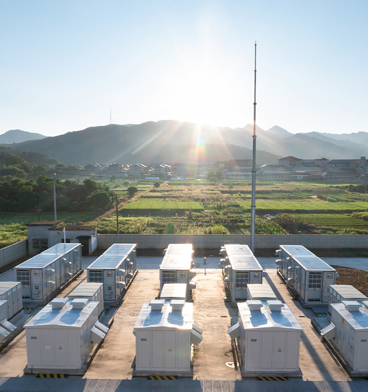 Battery energy storage system containers installed at a completed facility with surrounding landscape and mountains